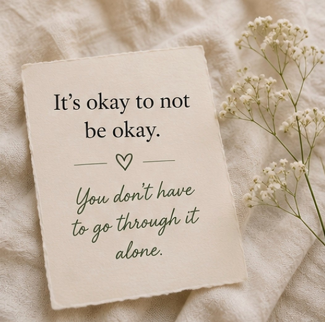 A handwritten card on linen that reads It's okay to not be okay. You don't have to go through it alone.